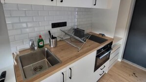 Una cocina moderna con armarios blancos, un lavamanos de acero inoxidable y una encimera de madera.