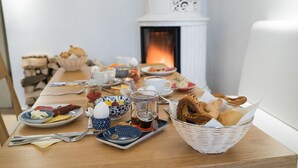A breakfast table with various dishes, a teapot, and a basket of bread. - Biohotel Schloss Kirchberg (Kirchberg an der Jagst)