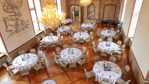 A spacious dining hall with multiple round tables, each set with white tablecloths and chairs, and a grand piano in the background. - Biohotel Schloss Kirchberg (Kirchberg an der Jagst)