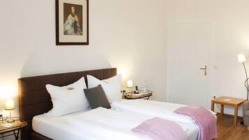 Una habitación de hotel ordenada con una cama grande, mesitas de noche, una lámpara de noche y un cuadro enmarcado en la pared.