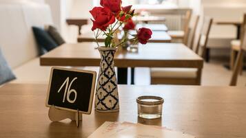 A dining table with a vase of red roses, a candle, and a blackboard with the number 16.