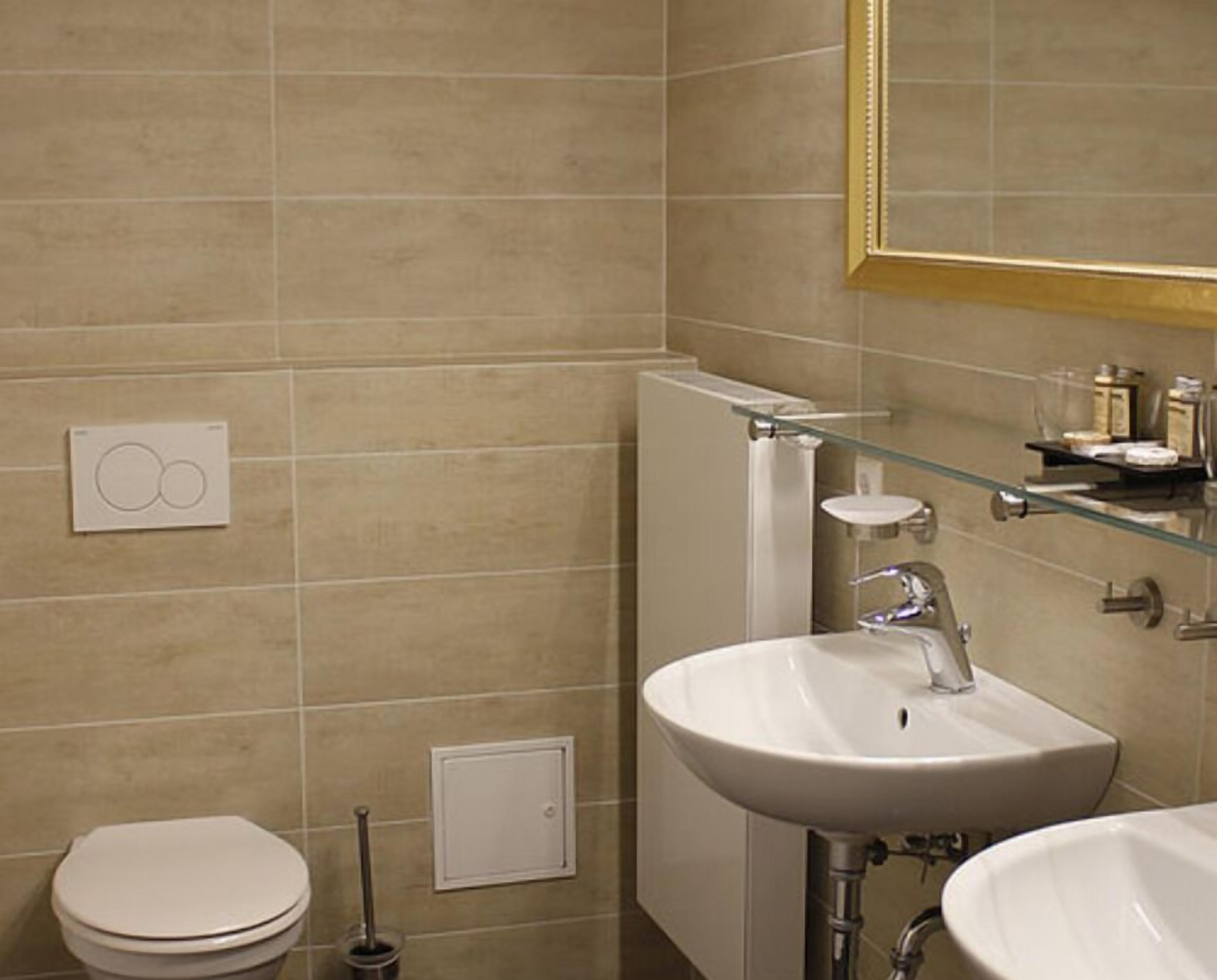 Un baño con inodoro, lavabo, espejo y perchero para toallas.