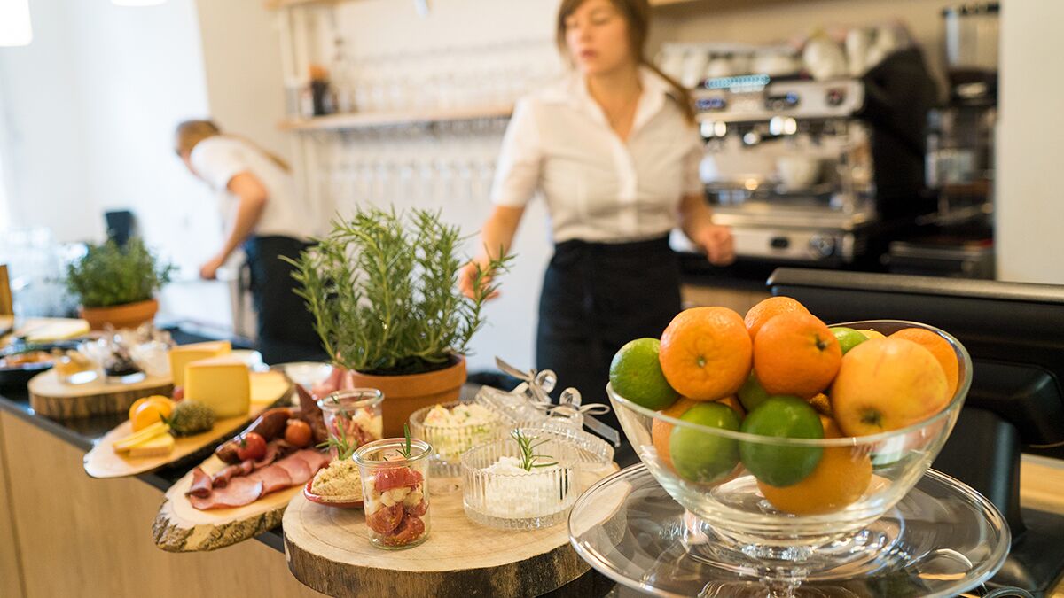 A buffet table with various food items and a bowl of fruits.