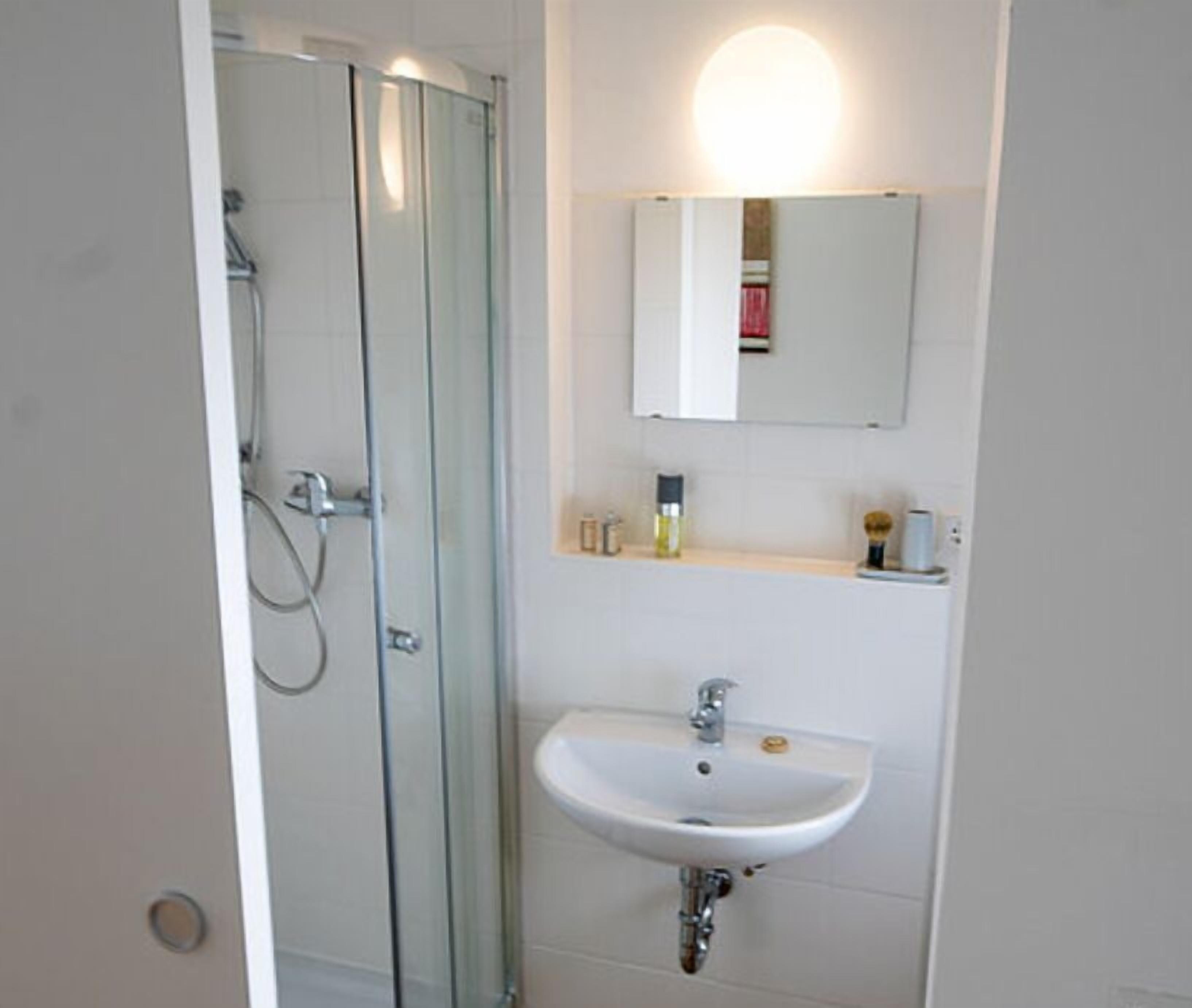 Une salle de bain avec une douche à parois de verre, un lavabo blanc et un miroir au-dessus.