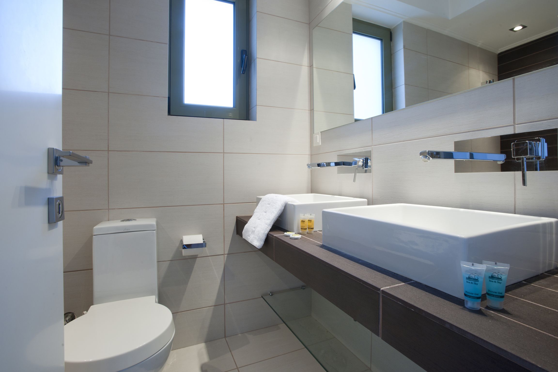 A modern bathroom with a toilet, a large sink, and a bathtub.