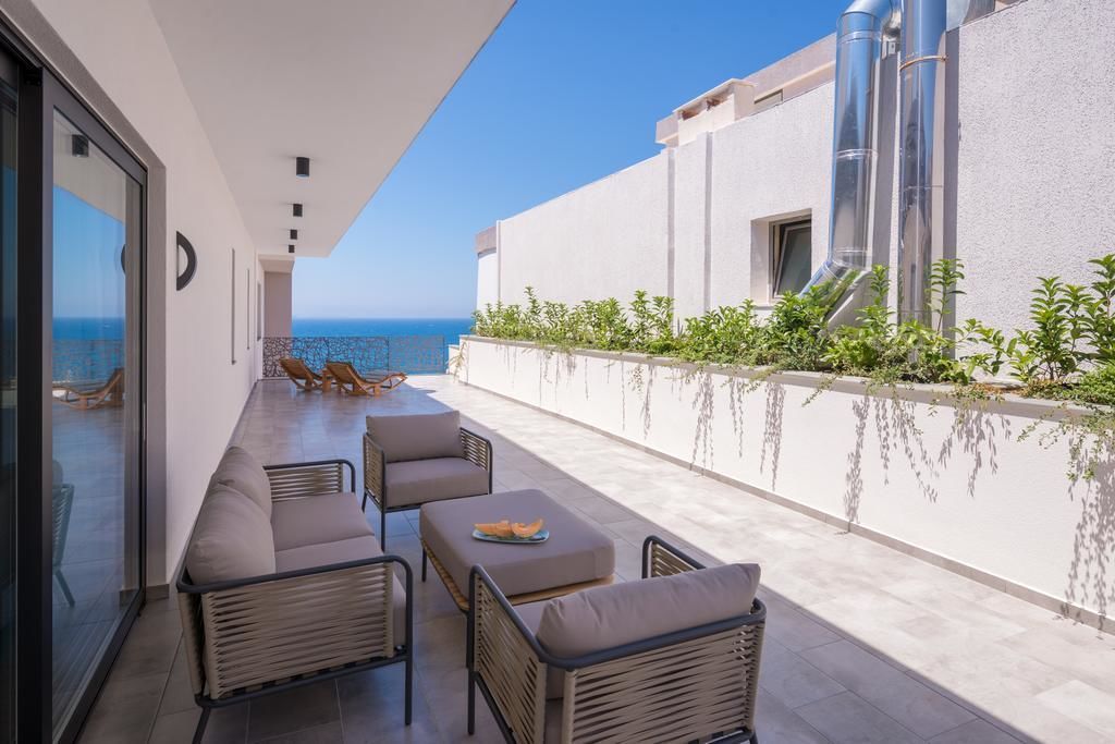 Patio esterno moderno con vista sul mare, con divano e tavolino.