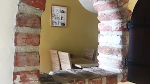An arched brick doorway leading to a room with a yellow wall and a framed picture. - Hotel Leopold (Bruges)