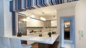 Una cocina moderna con armarios blancos, una isla central e iluminación colgante.