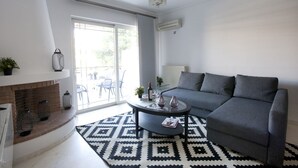Una sala de estar moderna con un sofá gris, un tapete de estampado blanco y negro, una mesa de centro redonda y una chimenea con adornos.