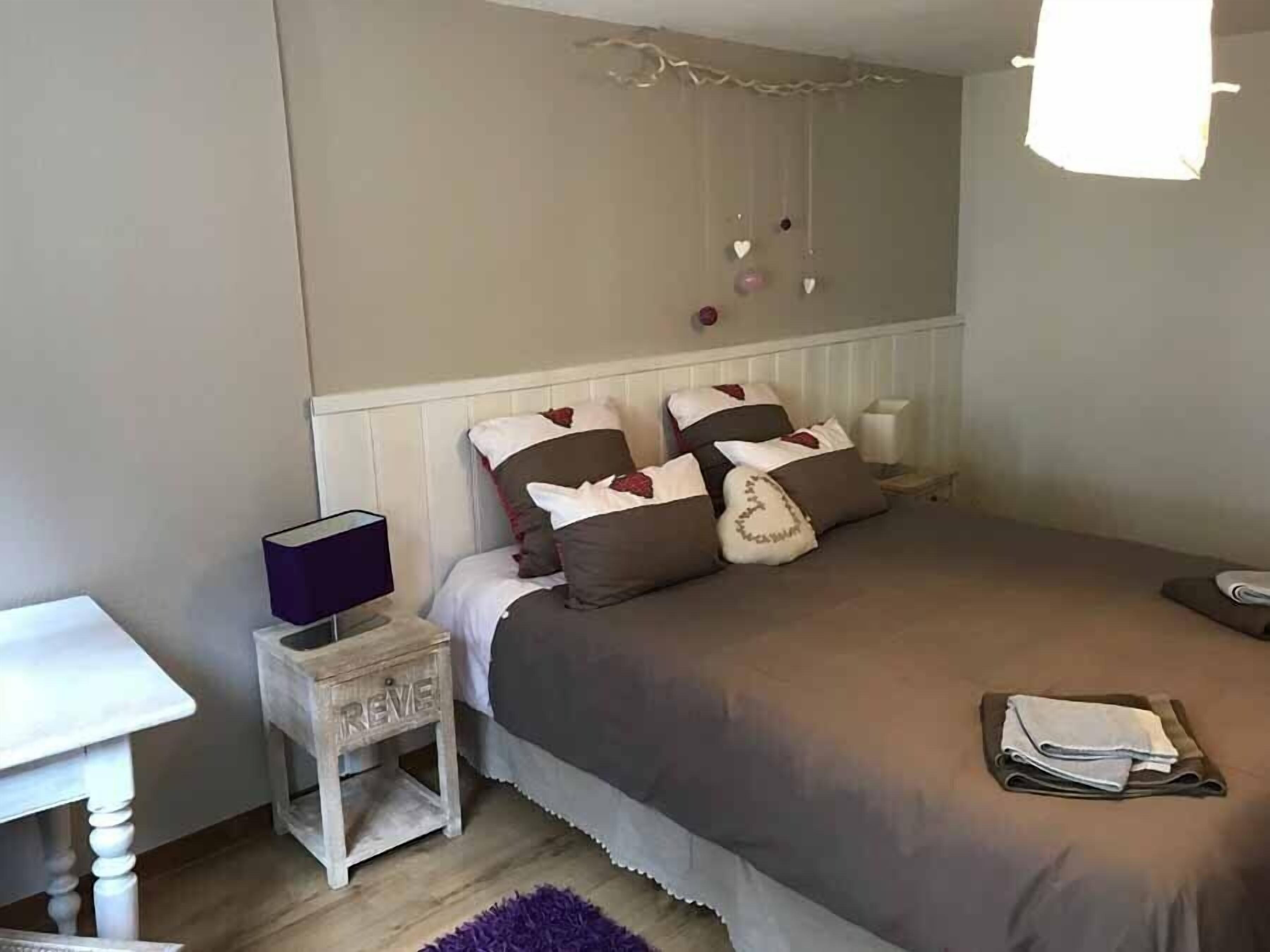 A bedroom with a bed, bedside table, and a small nightstand.
