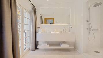 Une salle de bain moderne avec un grand miroir, une douche et une fenêtre avec des rideaux.