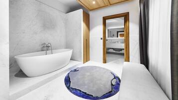 A modern bathroom with a freestanding bathtub, a round rug with a unique design, and a wooden ceiling.