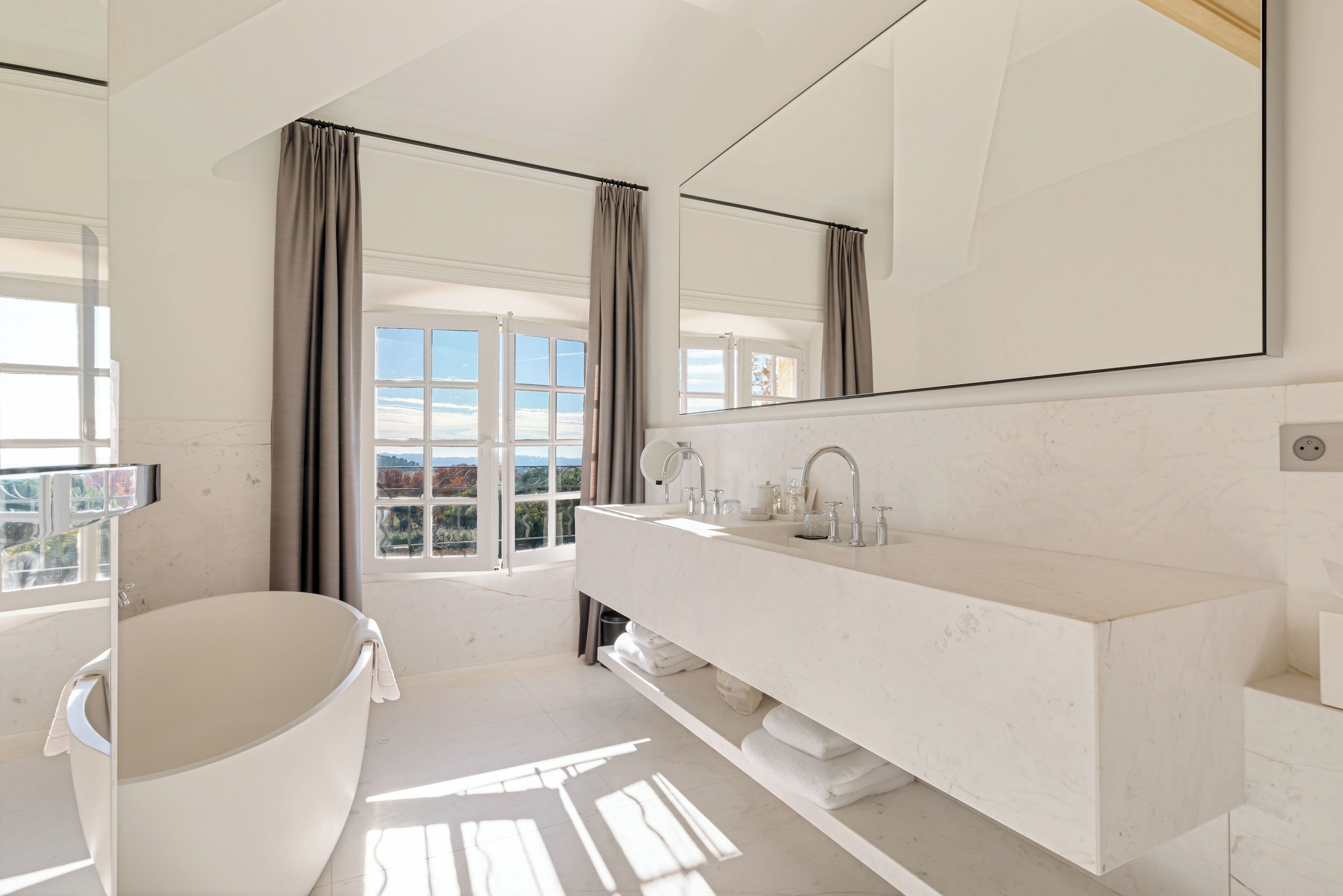 A modern bathroom with a freestanding bathtub, a large mirror, and a vanity with a sink.