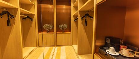 A hotel room with wooden flooring, a minibar, and a mirror.