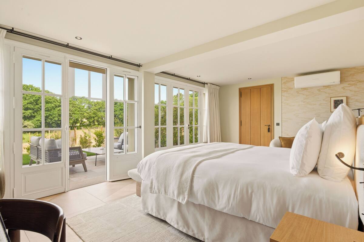 Ein Schlafzimmer mit einem großen Bett, einer Holztür und Blick ins Freie.