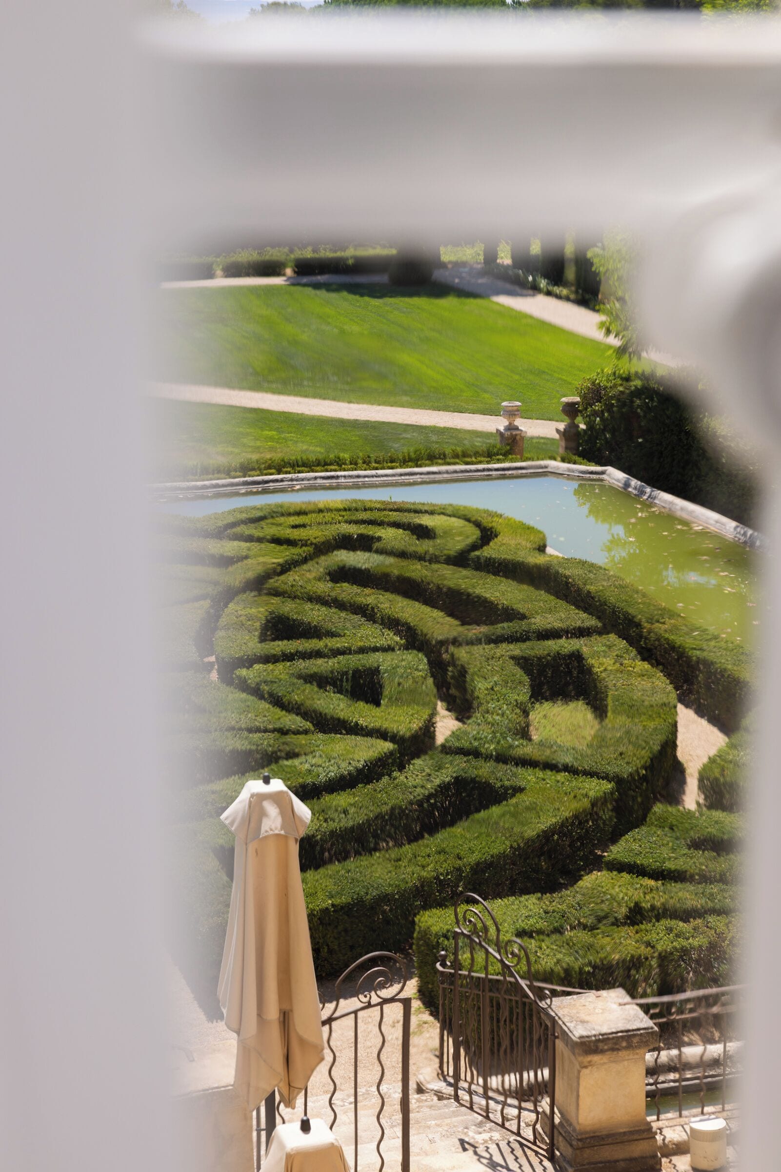 Un jardín ajardinado con un laberinto, una piscina y una escalera.