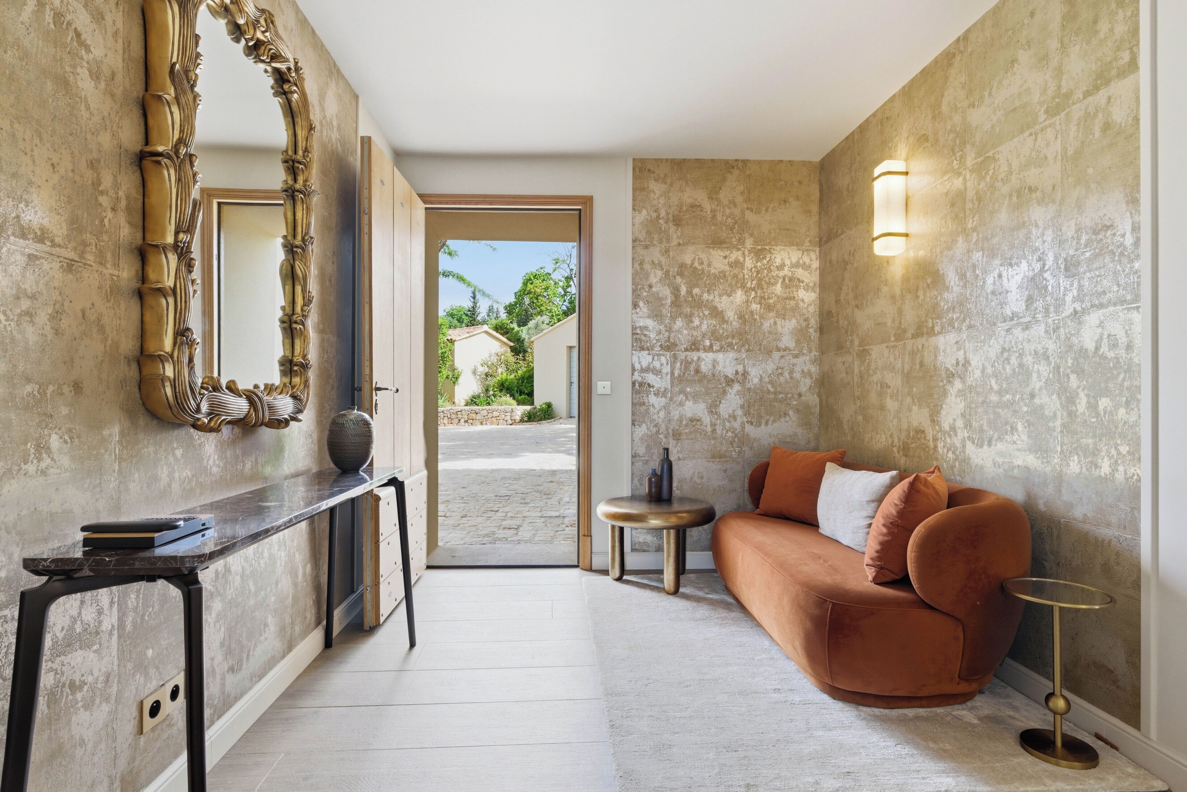 Un salon moderne comprenant un canapé, une table ronde, une console et un grand miroir.
