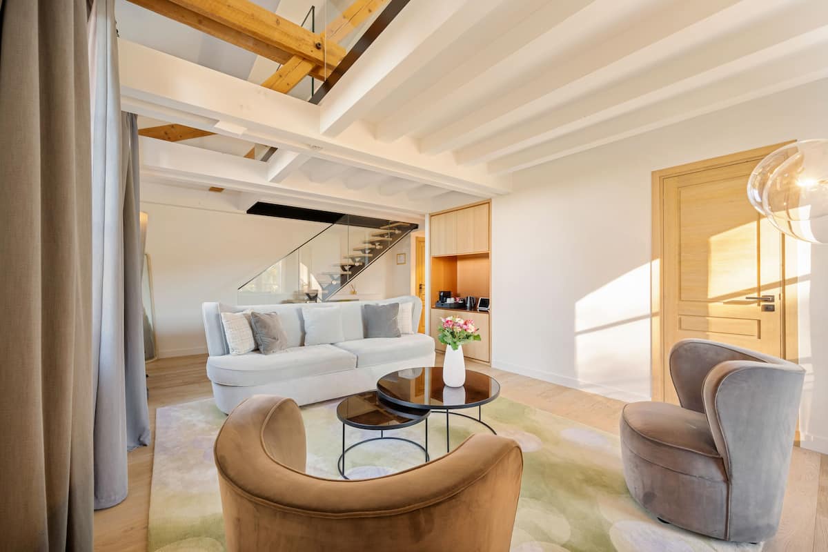 Ein modernes Wohnzimmer mit einer Couch, einem Couchtisch und einem Sessel. Eine Treppe führt zu einer weiteren Ebene.