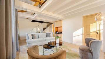 A modern living room with a sofa, a coffee table, and a chair. There is a staircase leading to another level.