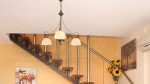 Un escalier au design moderne, un canapé agrémenté de coussins colorés, une table ornée d’objets décoratifs et un tableau représentant un vélo.