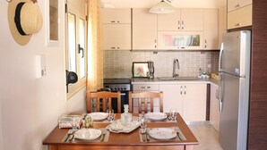 Une cuisine moderne avec des meubles en bois, un réfrigérateur en acier inoxydable et une table à manger pour quatre personnes.
