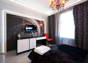 A modern hotel room with a large bed, a desk with a flat-screen TV, a red chair, and a large window with patterned curtains. - Partner Guest House Velyka Vasylkivska (Kyiv)