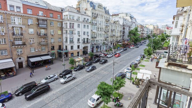 A street view of a city with multi-story buildings, parked cars, and pedestrians. - Partner Guest House Velyka Vasylkivska (Kyiv)