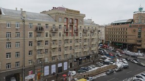 A multi-story building with balconies, a visible bank sign, and parked cars on the street. - Partner Guest House Velyka Vasylkivska (Kyiv)