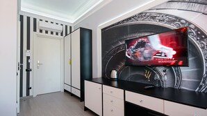 A modern living room with a large flat-screen TV mounted on a wall with a racing theme. There are black and white cabinets and a door with a striped pattern. - Partner Guest House Velyka Vasylkivska (Kyiv)