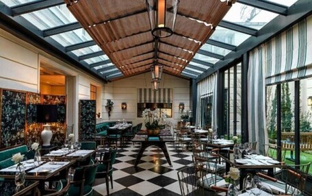 A restaurant with a checkered floor, high ceilings with a wooden slatted design, and large windows offering views of the outdoors.
