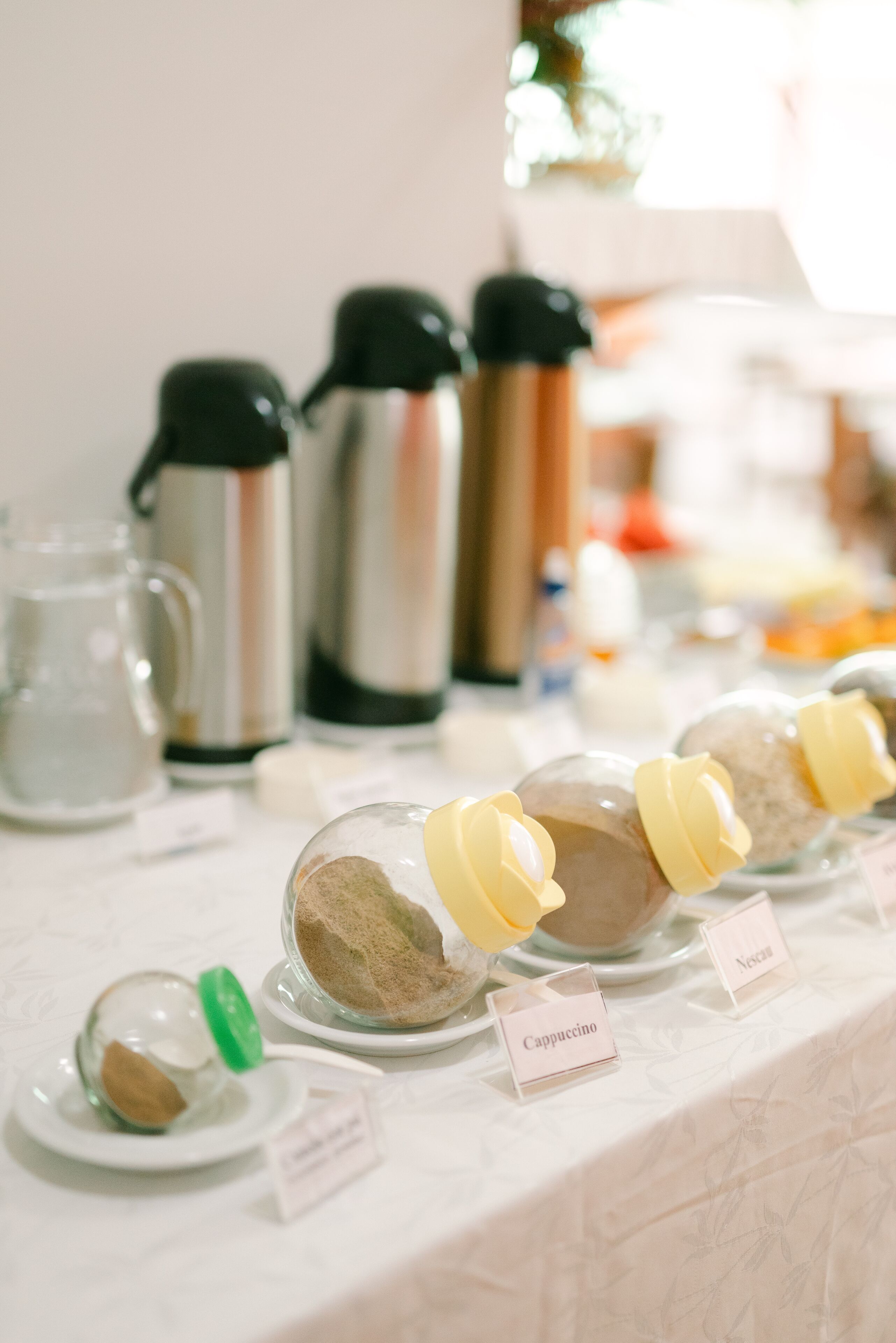 A table with labeled containers of coffee beans and a coffee maker.