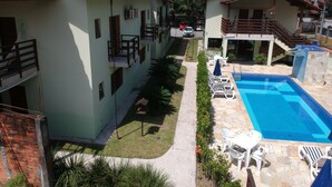 A residential building with a swimming pool, outdoor seating, and a garden area. - Hotel Kiribati (São Sebastião)
