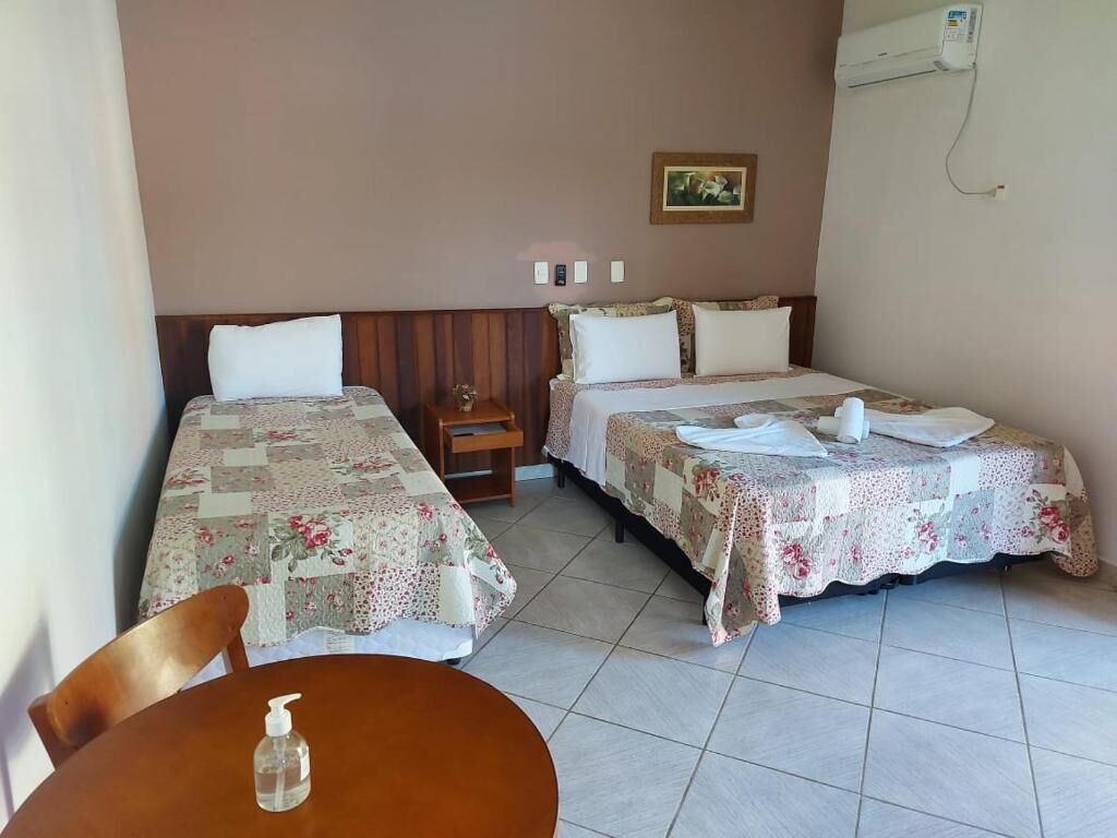 A hotel room with two beds, a small table, and a chair.