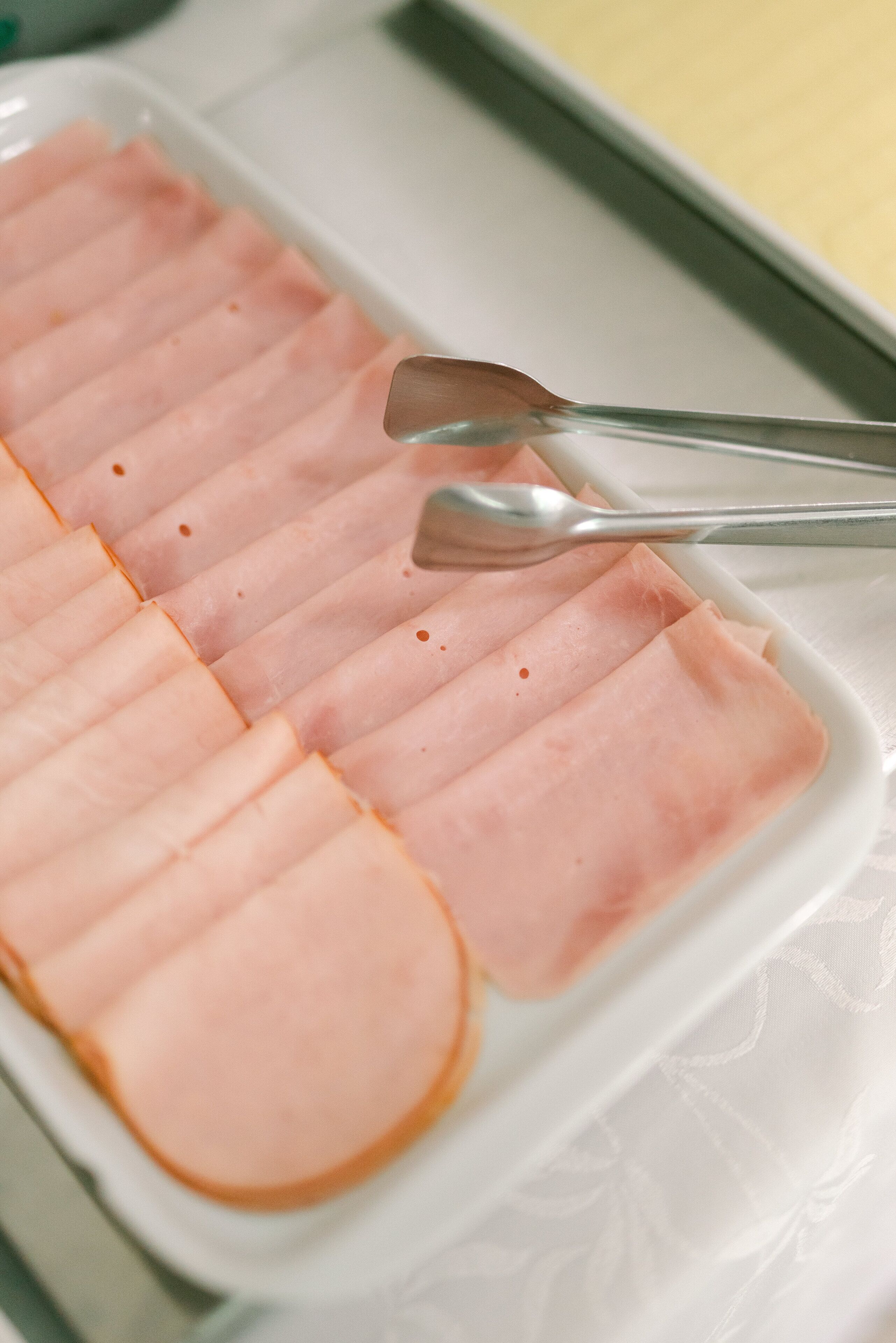 A white plate with neatly arranged slices of ham.