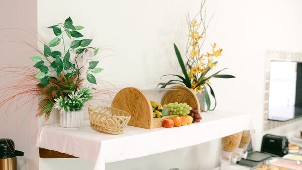 A buffet table with various food items and decorative plants. - Hotel Kiribati (São Sebastião)