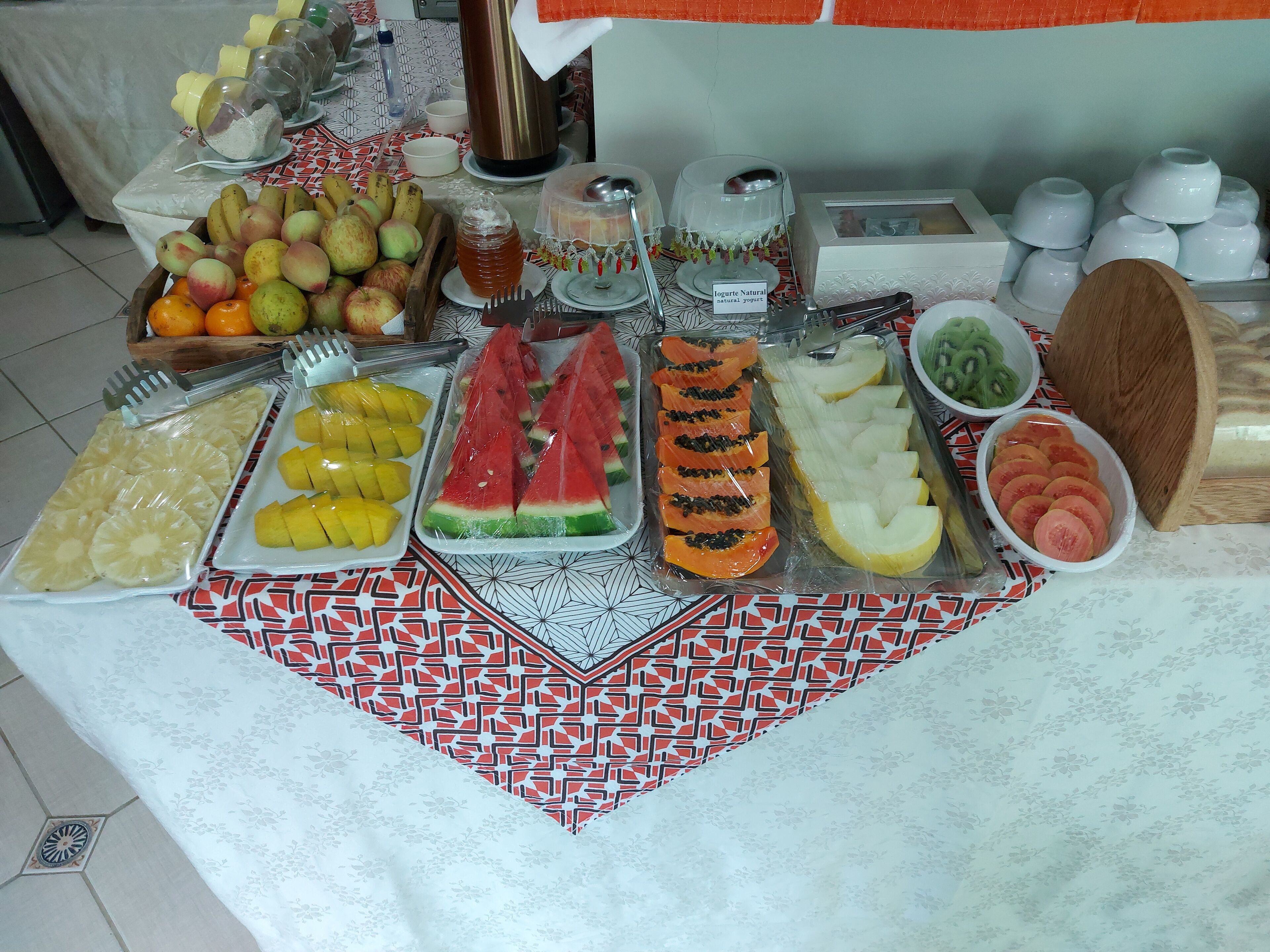 Una mesa con varias frutas y un recipiente de yogur.