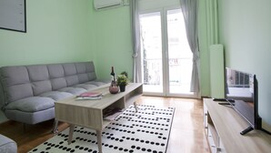 Un salon avec un canapé gris, une table basse en bois, un téléviseur et un balcon avec vue.