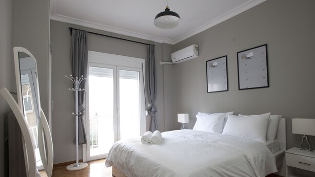 Une chambre moderne avec un grand lit, une table de chevet, une armoire et un luminaire au plafond.
