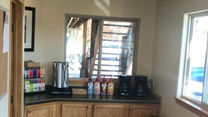 Una piccola cucina accessoriata con mobili in legno, una macchina del caffè e un cestino.
