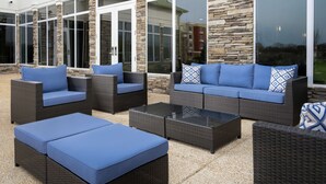 An outdoor patio area with wicker furniture and stone pillars. - Hilton Garden Inn Olive Branch, MS (Olive Branch)