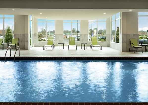A pool area with chairs and tables, large windows, and a view of the parking lot.