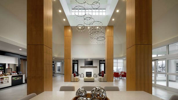 A spacious lobby with a modern chandelier, wooden pillars, and a seating area with sofas and chairs. - Hilton Garden Inn Olive Branch, MS (Olive Branch)