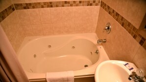 A bathroom with a bathtub, a sink, and a shower curtain. - Swan Motel (Linden)