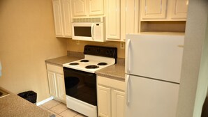 A kitchen with white cabinets, a white stove, a white microwave, and a white refrigerator. - Swan Motel (Linden)