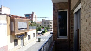 A balcony with a view of a street, a building with a sign for a real estate agency, and a clear sky. - Habitaciones Petrer (Petrer)