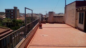 A rooftop terrace with a brick floor, metal railing, and a view of surrounding buildings. - Habitaciones Petrer (Petrer)