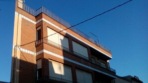 A multi-story building with a brick facade, balconies, and large windows. - Habitaciones Petrer (Petrer)