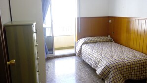 A small, single-bed room with a wooden headboard, a wardrobe, and a balcony with a view. - Habitaciones Petrer (Petrer)