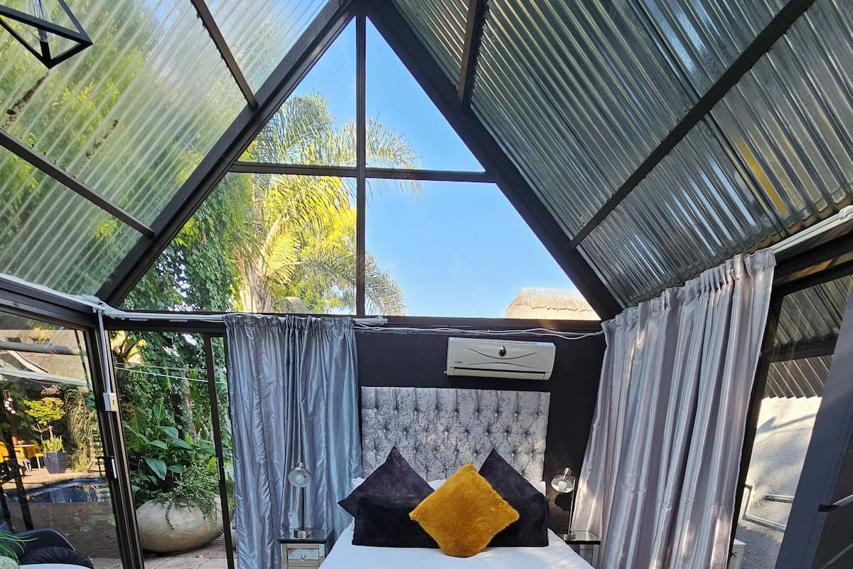 Un dormitorio con cama, ventana grande y vistas al exterior.