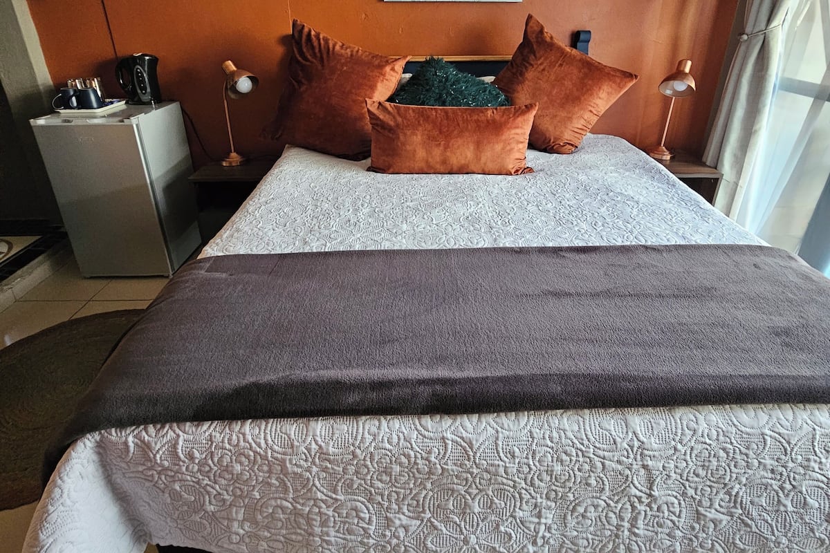 Una cama bien hecha con un edredón estampado, dos almohadas y una caja decorativa.